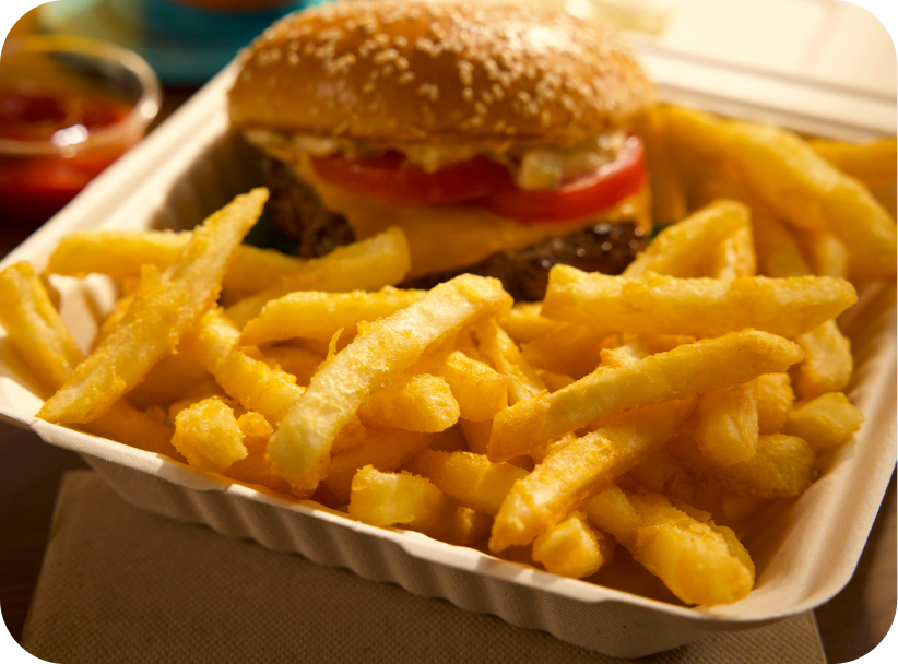 Close-up of McCain® SureCrisp® fries paired with a burger in a takeout container.